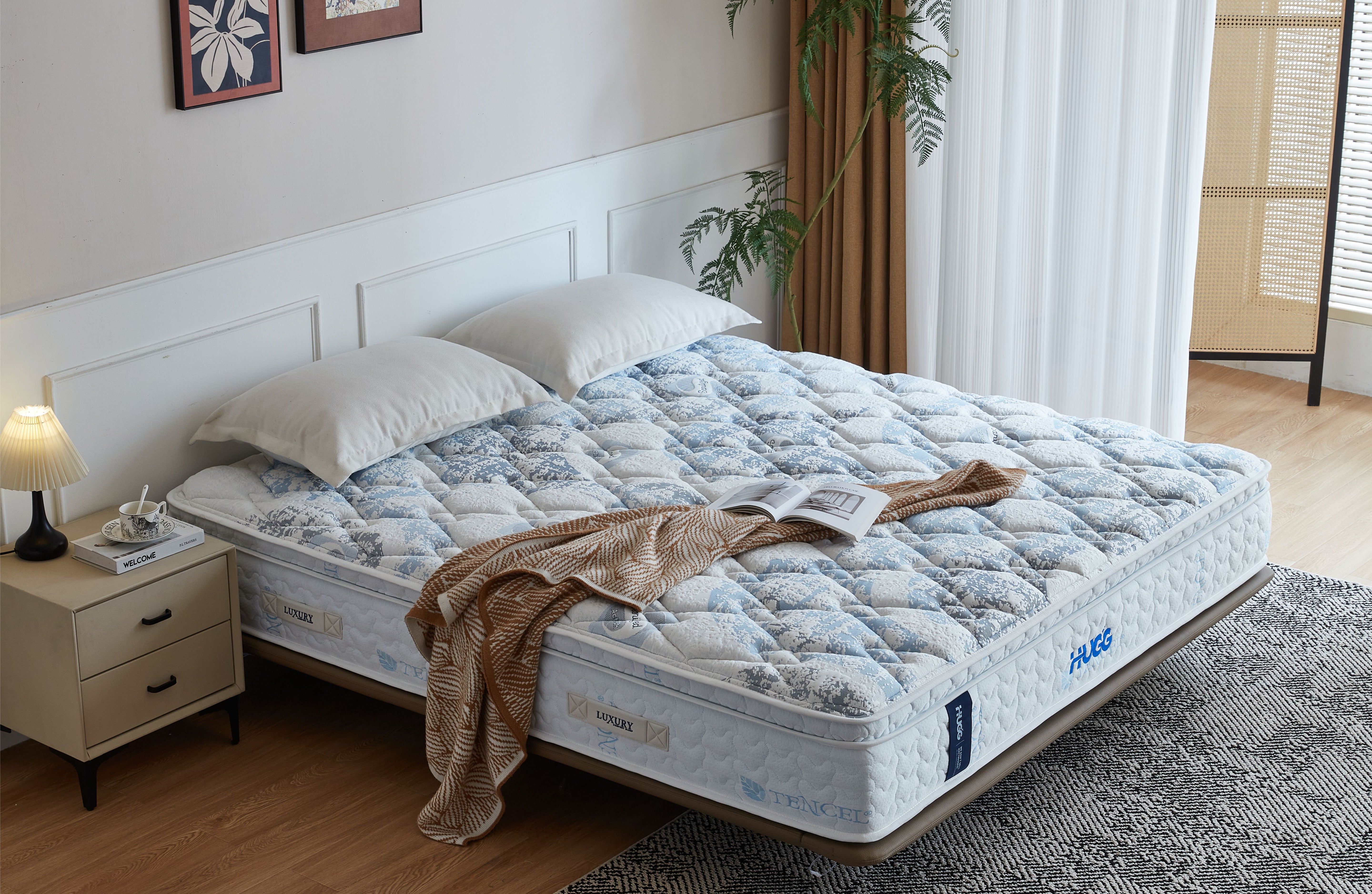Mattress with decorative blanket and pillows in a bedroom setting
