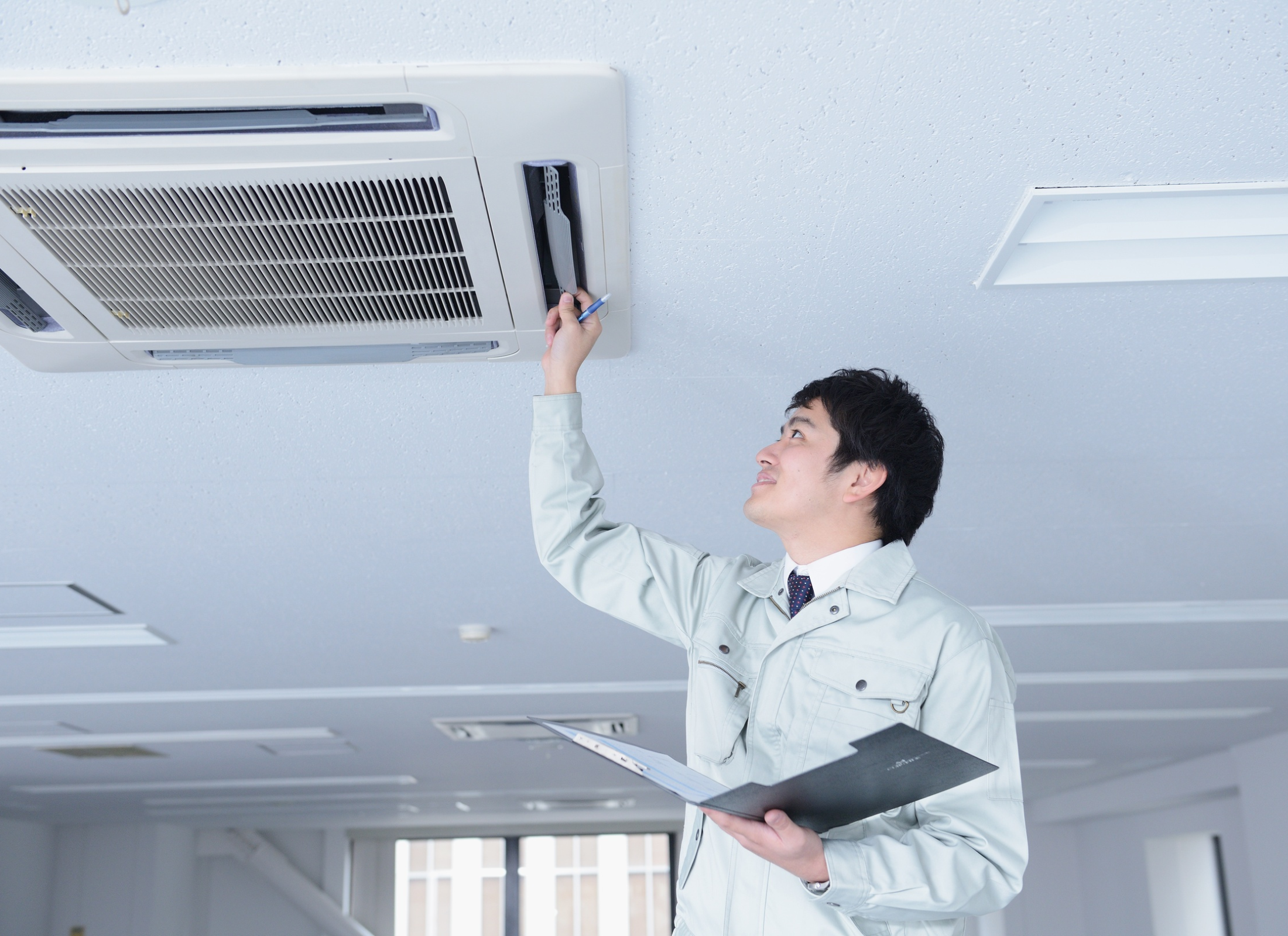 Person inspecting an air conditioning unit in a well-lit room
