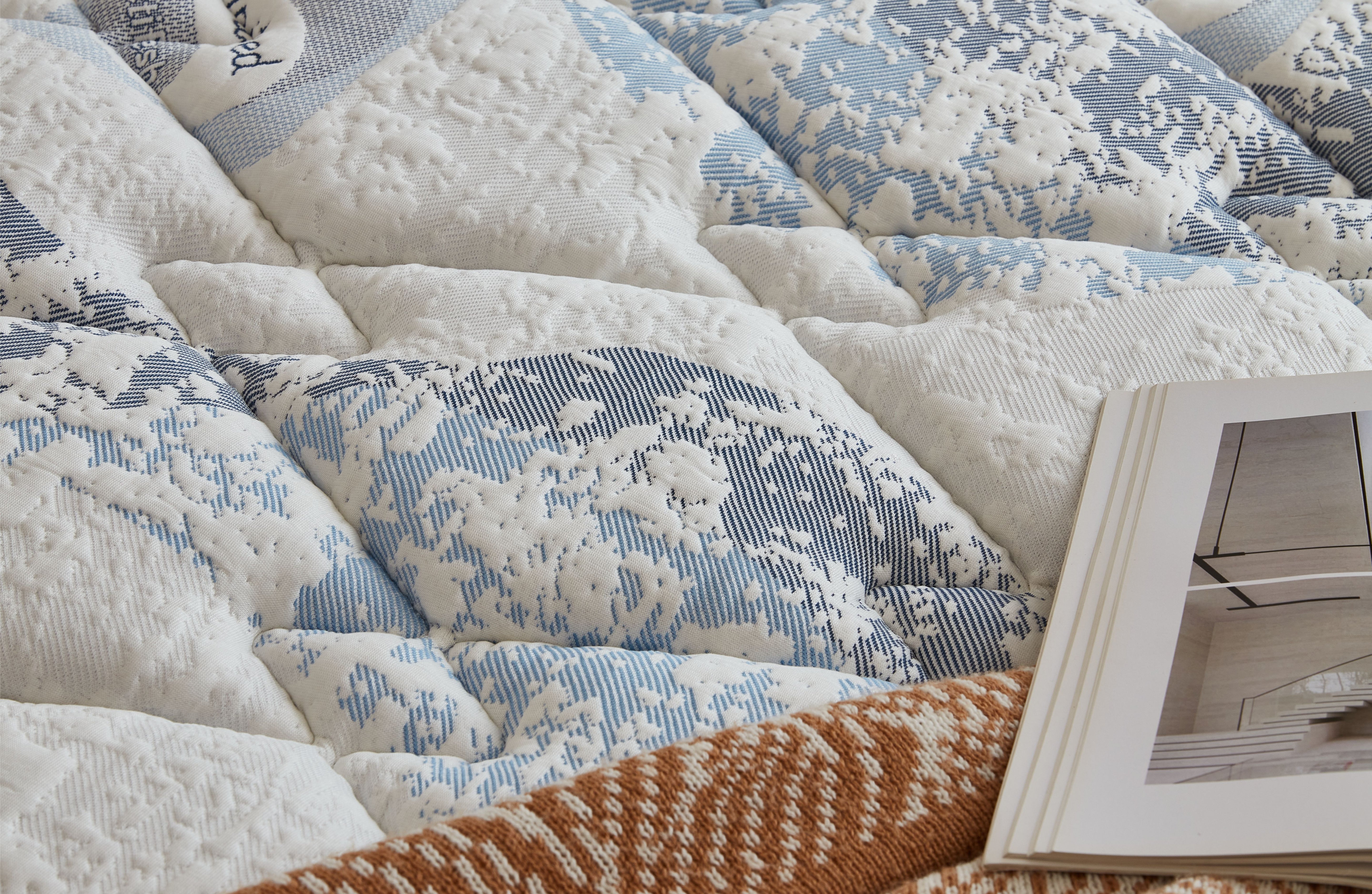Close-up of a quilt with geometric pattern and a book on top