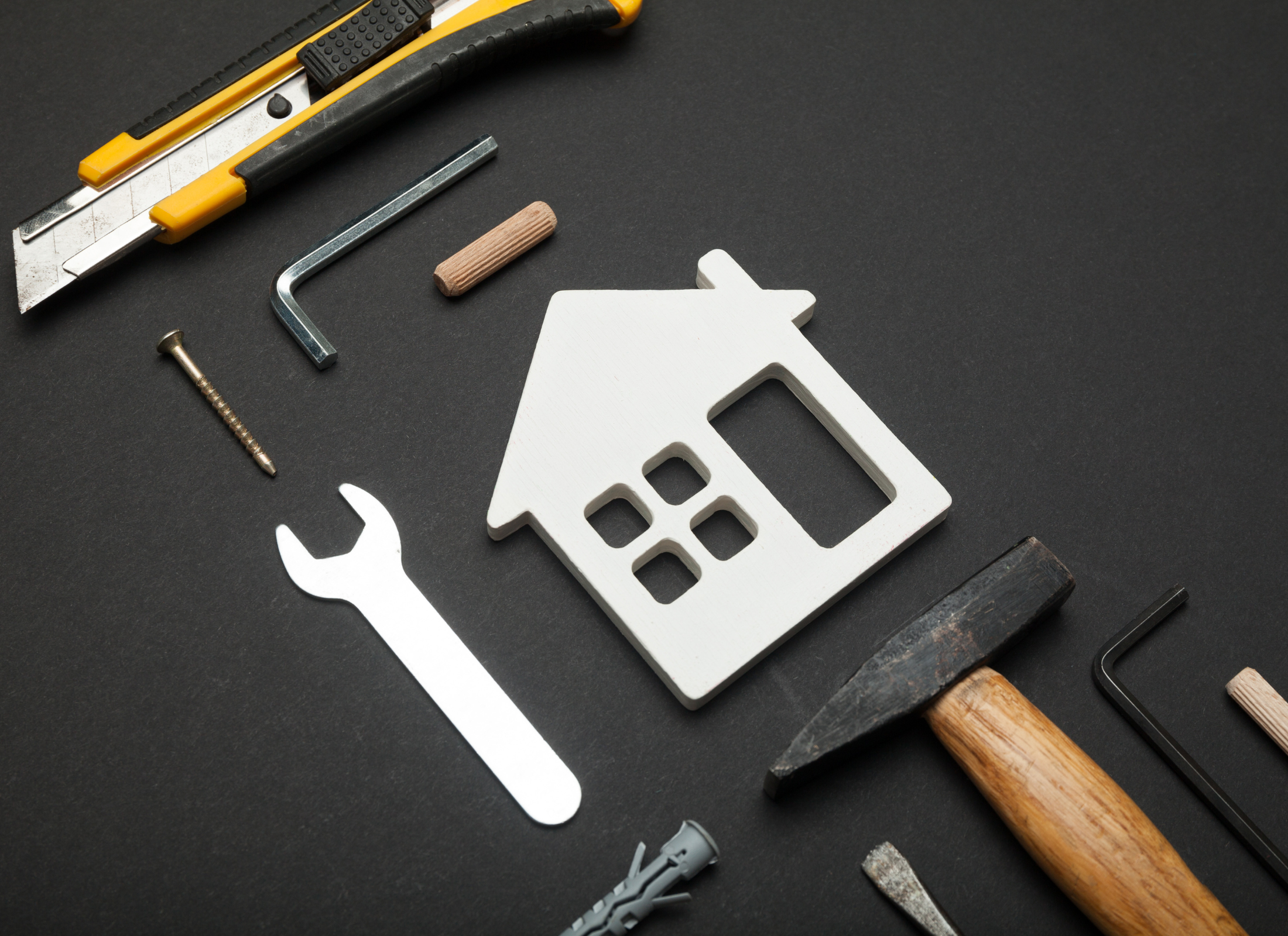 Tools and a house-shaped metal cutout on a black background